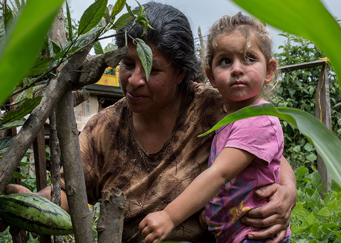 woman carrying a young girl as she picks crops