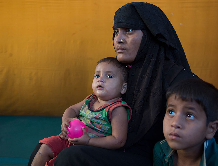 Setara Begum sits with her Children Ashmila Bibi and Yasmun as other children are cared for in Action Against Hunger's child friendly space