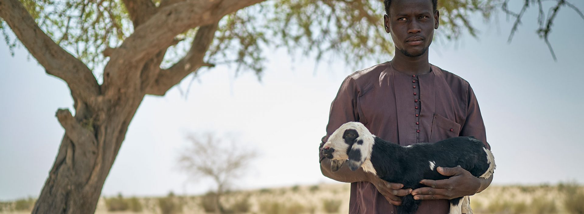 A man holds a goat at an Action Against Hunger project in Chad.