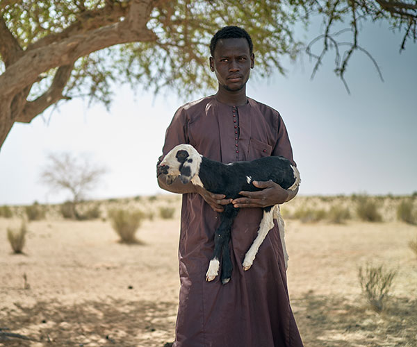 A man holds a goat at an Action Against Hunger project in Chad.