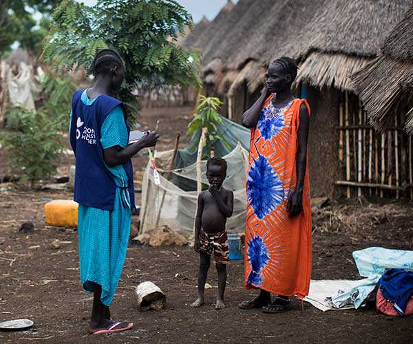 South Sudanese refugees supported by an Action Against Hunger member of staff.