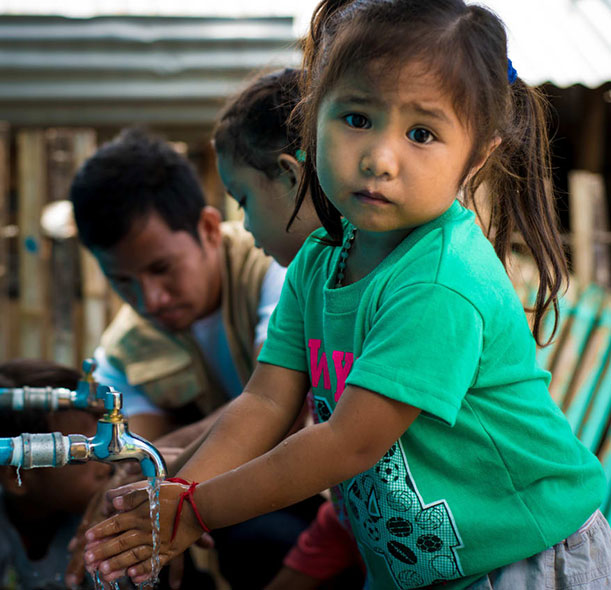 A girl washes her hands in the Philippines.