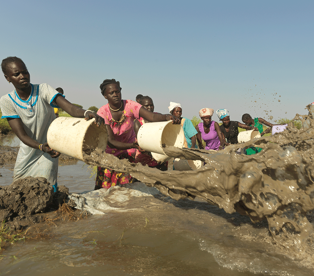 Woman of different communities in Old Fangak volunteer to drain the flooded airstrip - their only way in or out of the area - South Sudan 