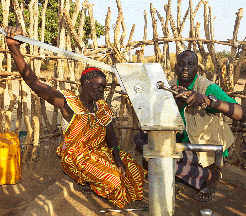 John from Action Against Hunger teaches Nyanut how to repair the borehole at Baackuel Village, Malualkon, South Sudan.