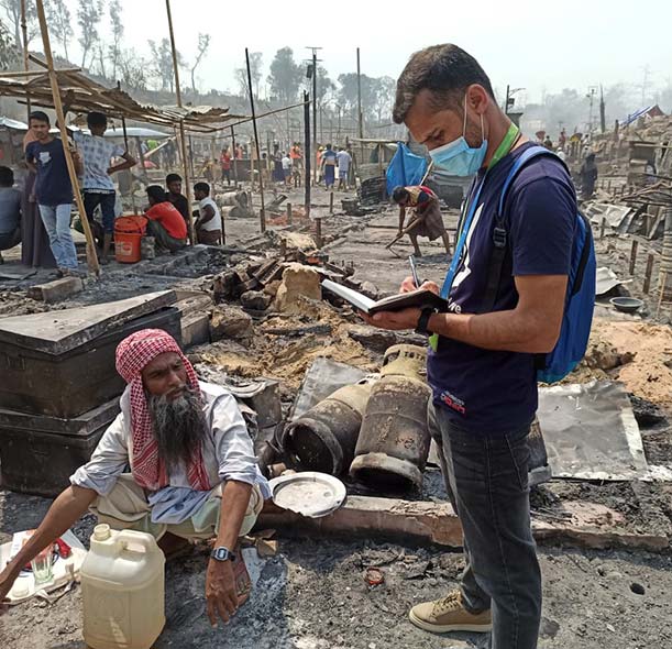 An Action Against Hunger staff member helps a man affected by the fires at a Rohingya refugee camp in Cox's Bazar, Bangladesh.