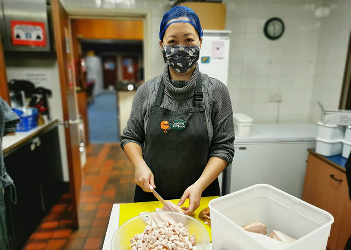 A volunteer cooks a meal at Cracking Good Food in Manchester.