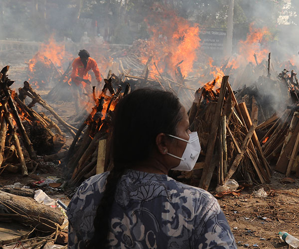 A family member looks on at funeral pyres of victims of coronavirus in India.