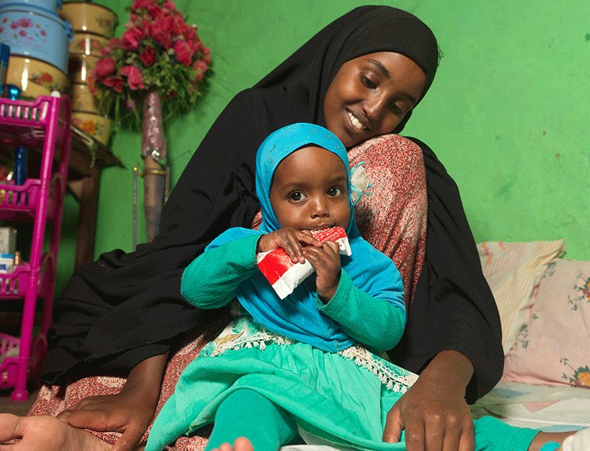 Medina with her daughter Munira who is eating therapeutic food given to them at the Action Against Hunger supported malnutrition treatment centre in Ethiopia