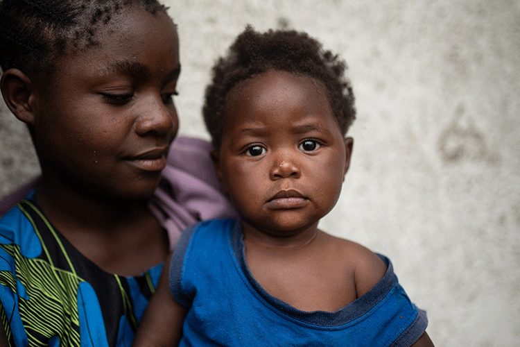 Alice Mwishe (13 years old) with her little sister Olivine, outside a school in the DRC