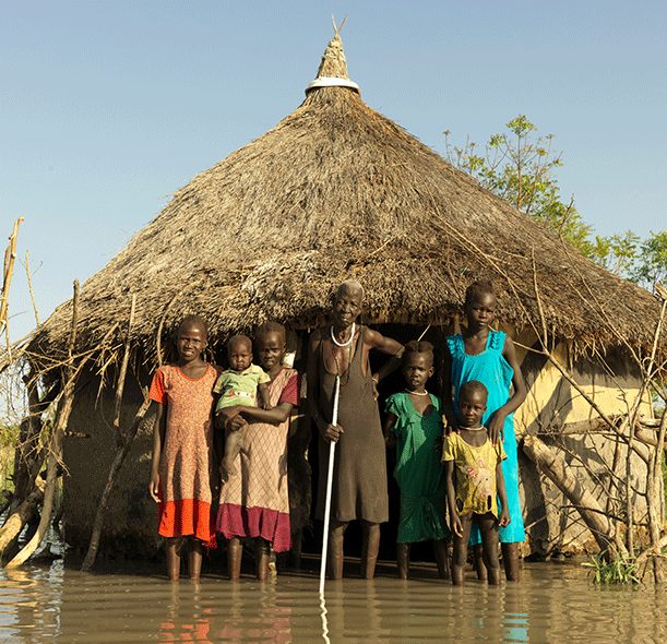 Family in South Sudan stand in front of their home which has been flooded