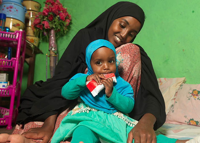 Medina with her daughter Munira who is eating therapeutic food given to them at the Action Against Hunger supported malnutrition treatment centre in Ethiopia