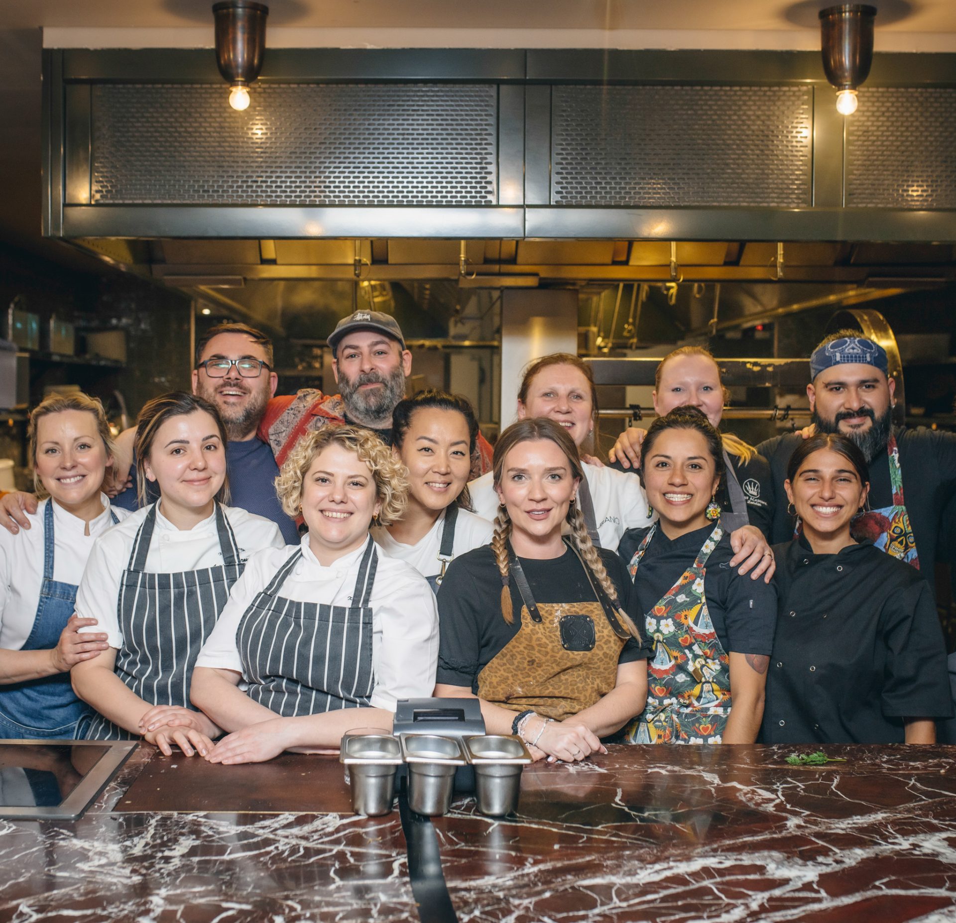 Group of chefs standing in open-plan ktichen smiling at Action Against Hunger event