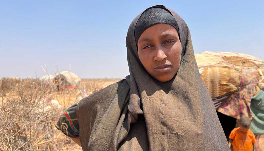A photo of Mumina, a woman who walked 10 miles with her three children to find food and water.