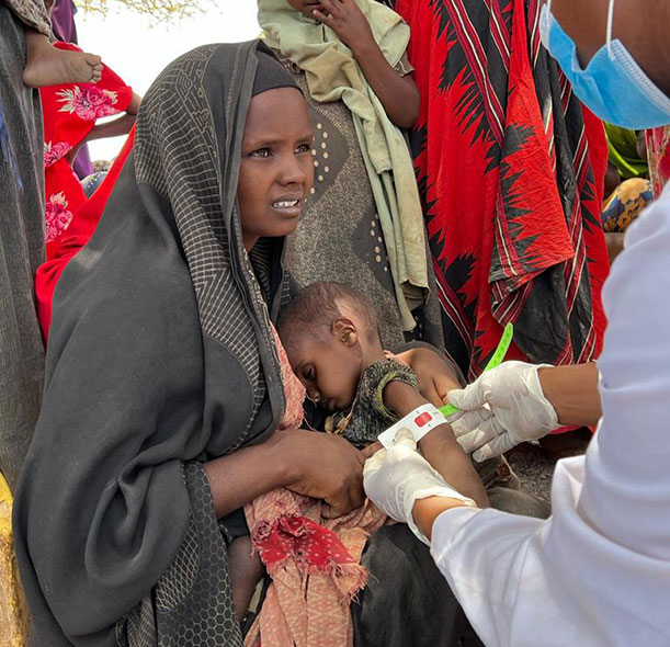 A member of Action Against Hunger’s mobile team measures Aftin’s child’s arm to check them for malnutrition.