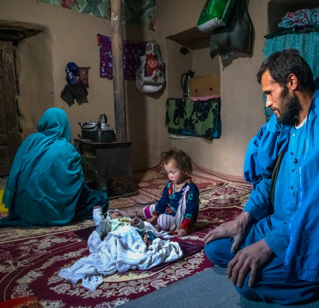 Family in Afghanistan (man, women and young child) sitting on the floor in their home