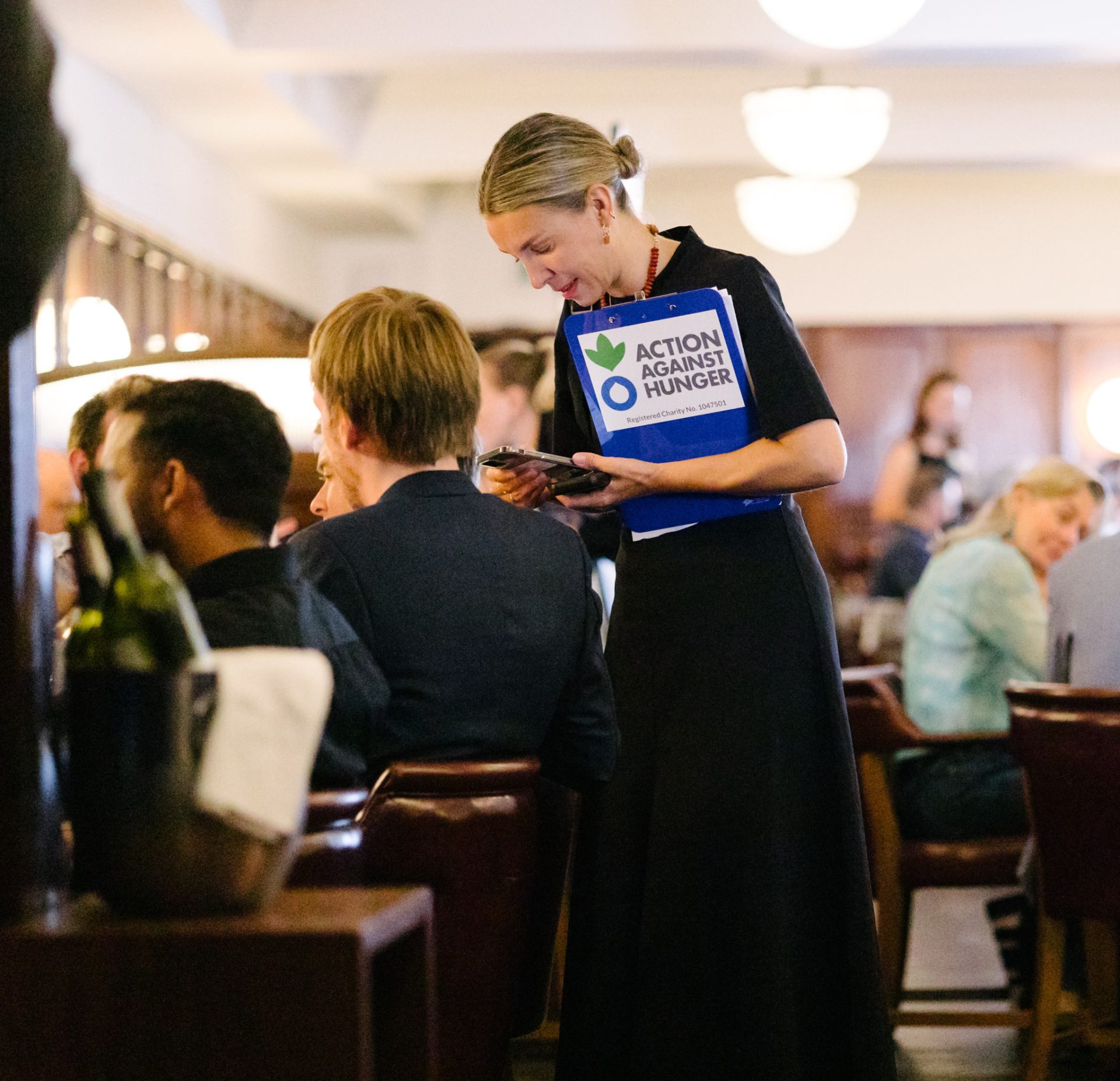 Action Against Hunger volunteer speaking to attendee at dinner event, Hawksmoor dining room