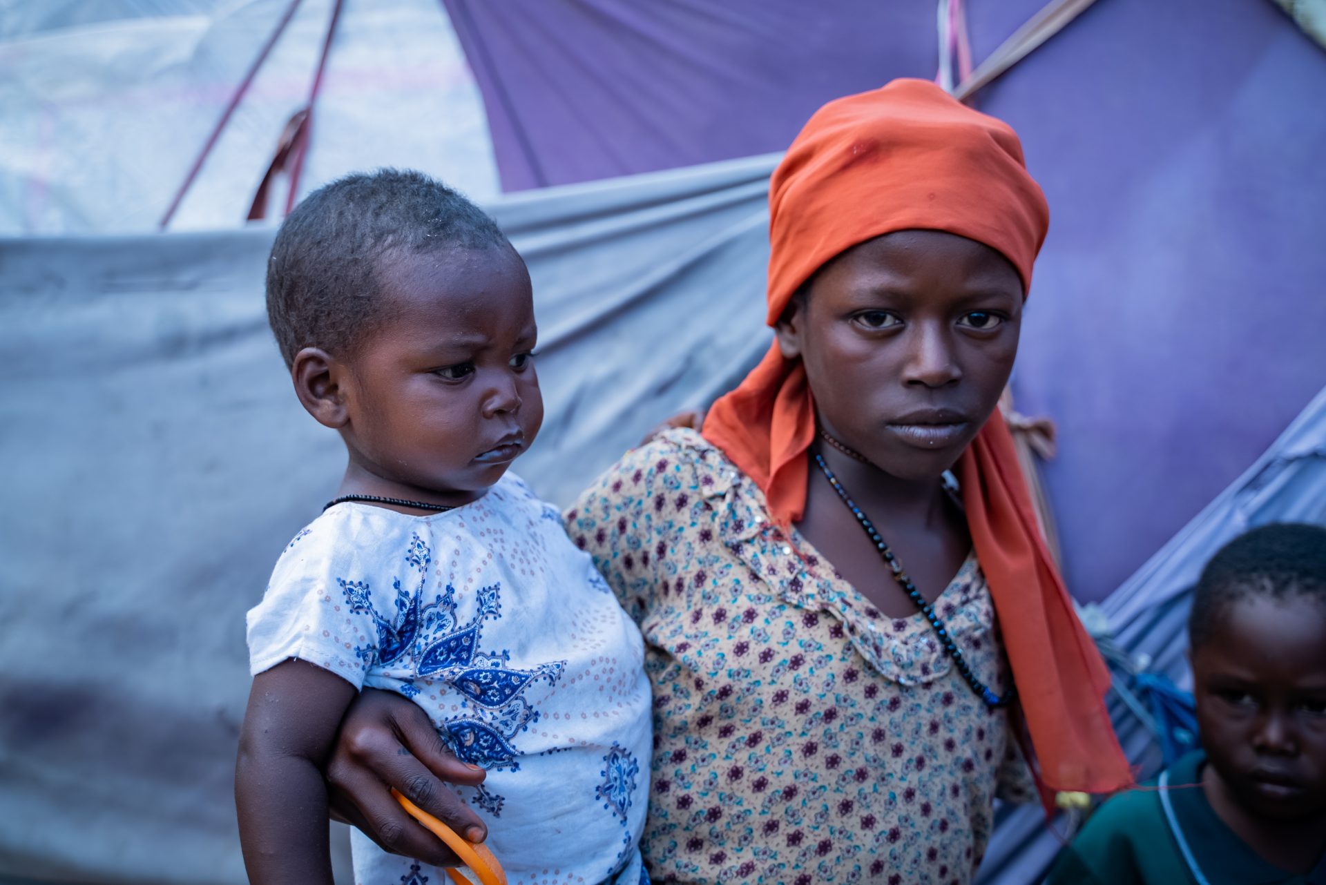 A young girl holding her baby brother in a displacement camp in Somalia