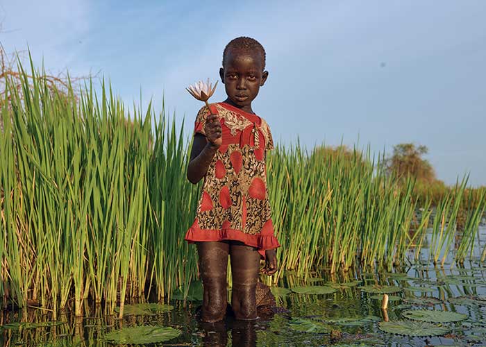 Nyamile holds a lily she's picked near her home in South Sudan.