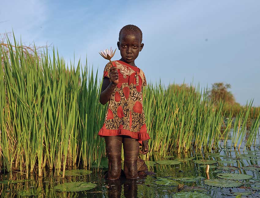Nyamile holds a lily she's picked near her home in South Sudan.