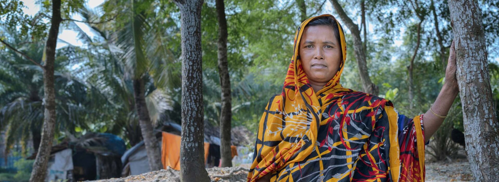 Rohima in Bangladesh standing among trees wearing colourful sari.