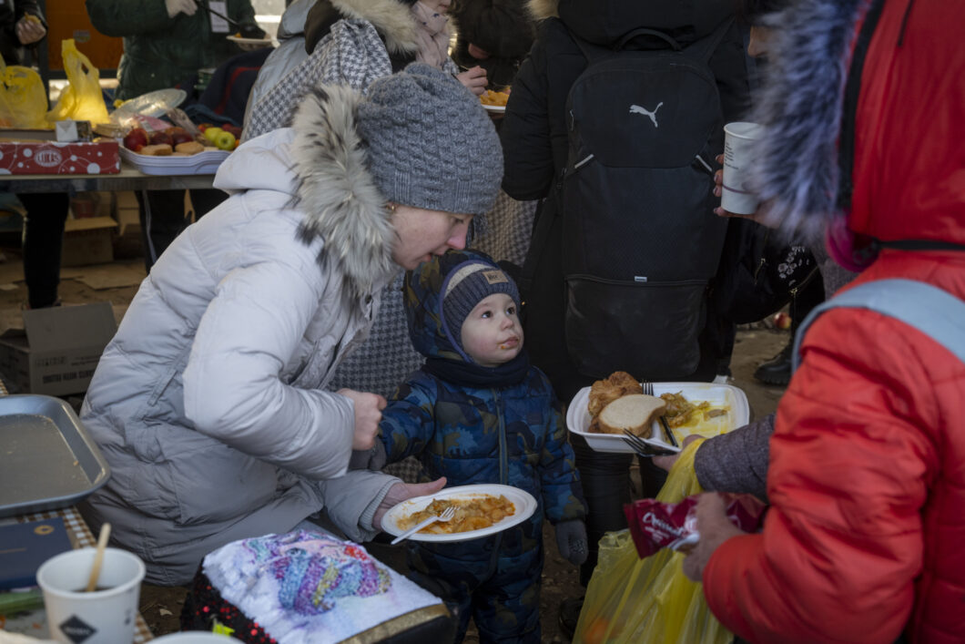 A refugee and her child holding a plate of food