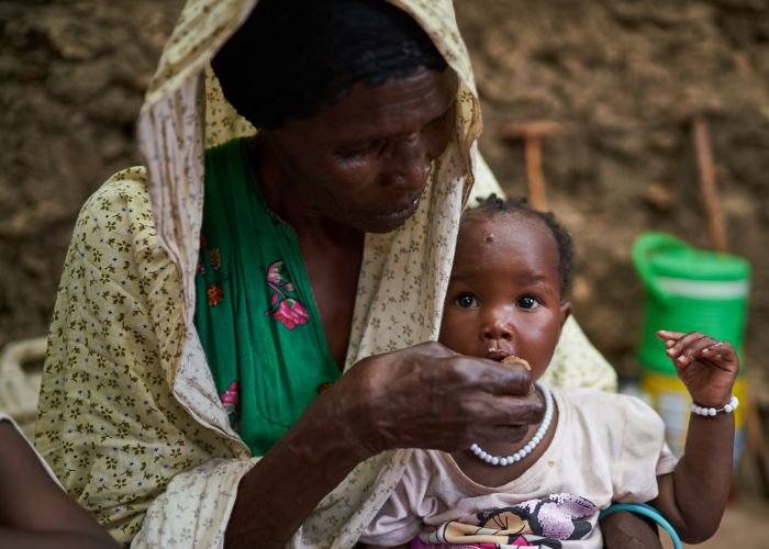 Moura, a Sudanese refugee, feeding her child Hamida specialist nutritional food.