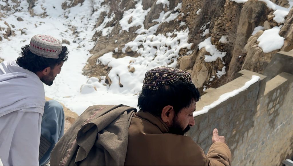 Farmers in Afghanistan sitting next to snowy mountains.