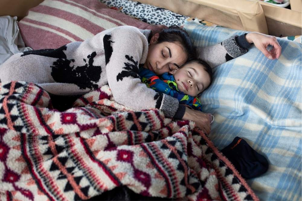 A mother and child sleeping in blankets