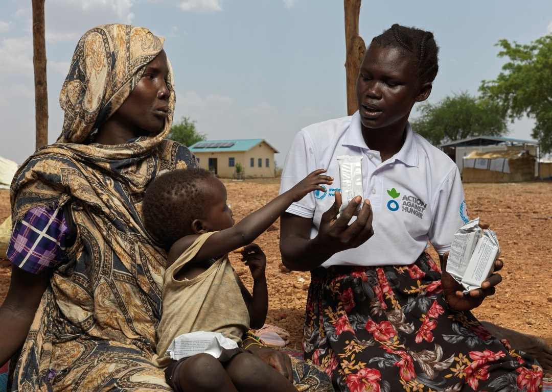 An Action Against Hunger worker giving therapeutic food to a child