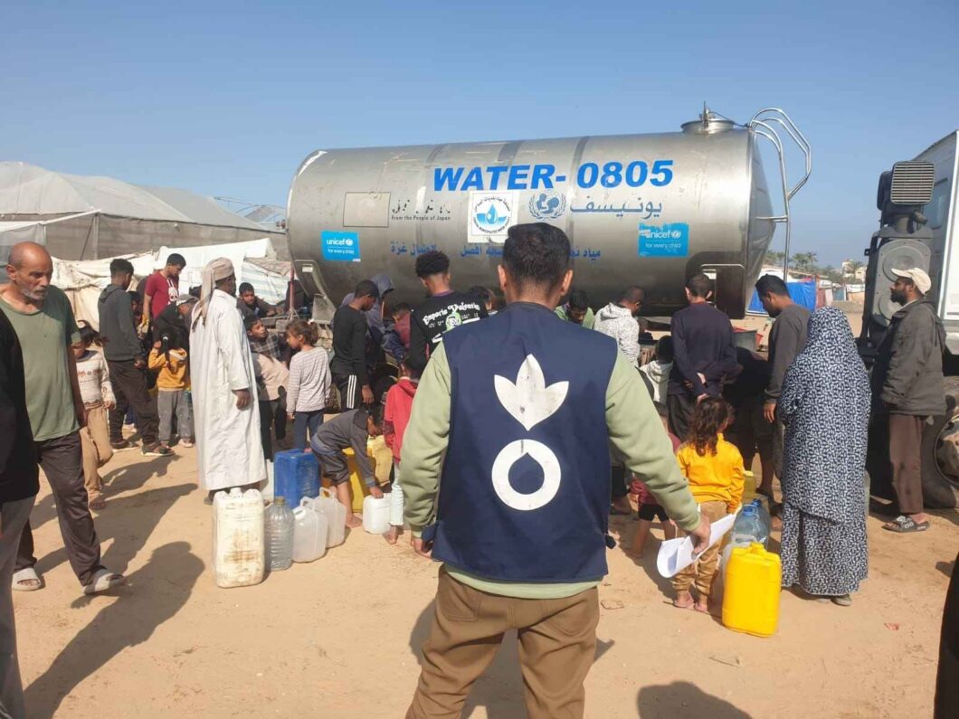 Action Against Hunger staff in Gaza standing in front of a water tank.