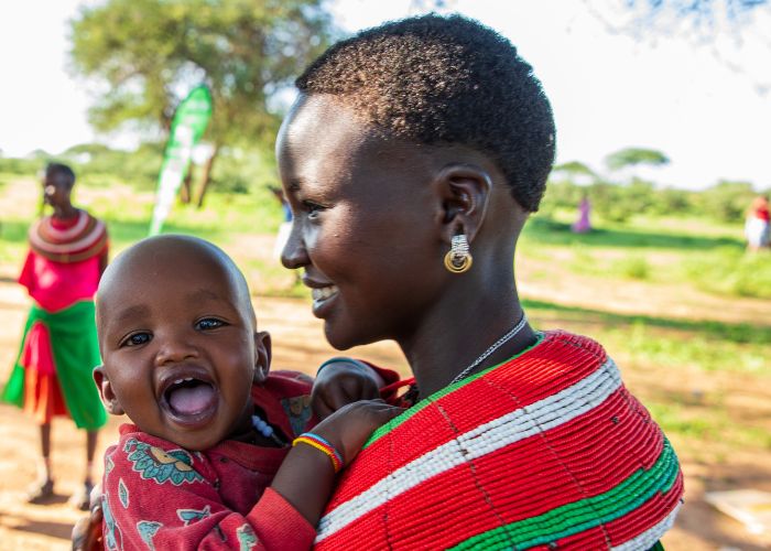 Woman in Kenya holding her smiling baby.