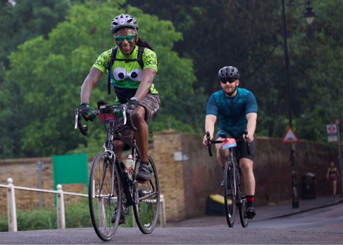 Two men cycling along road lines with trees.