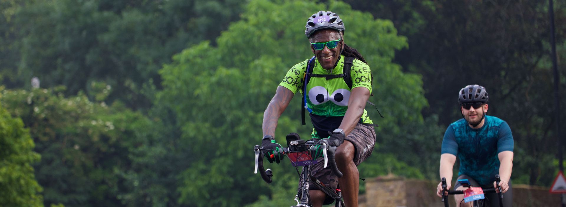 Two cyclists riding bikes smiling.