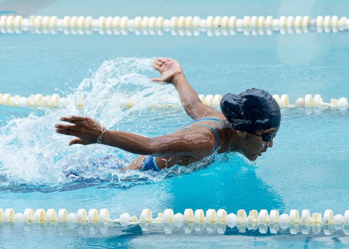 Woman in swimming hat doing butterfly stroke in pool.