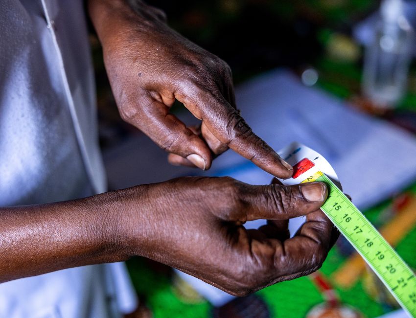 An Action Against Hunger staff member in Chad shows how to use a MUAC band to screen children for malnutrition.